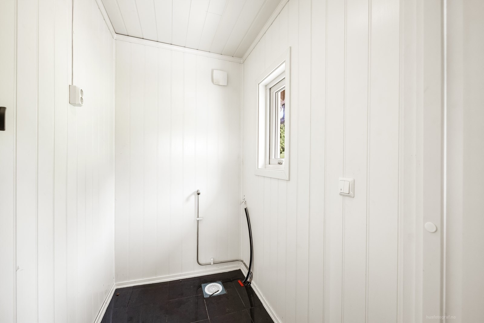 Praktisk rom med flislagt gulv og sluk, i dag benyttet som bod. Rommet har avtrekksvifte montert på vegg. Galleribilde