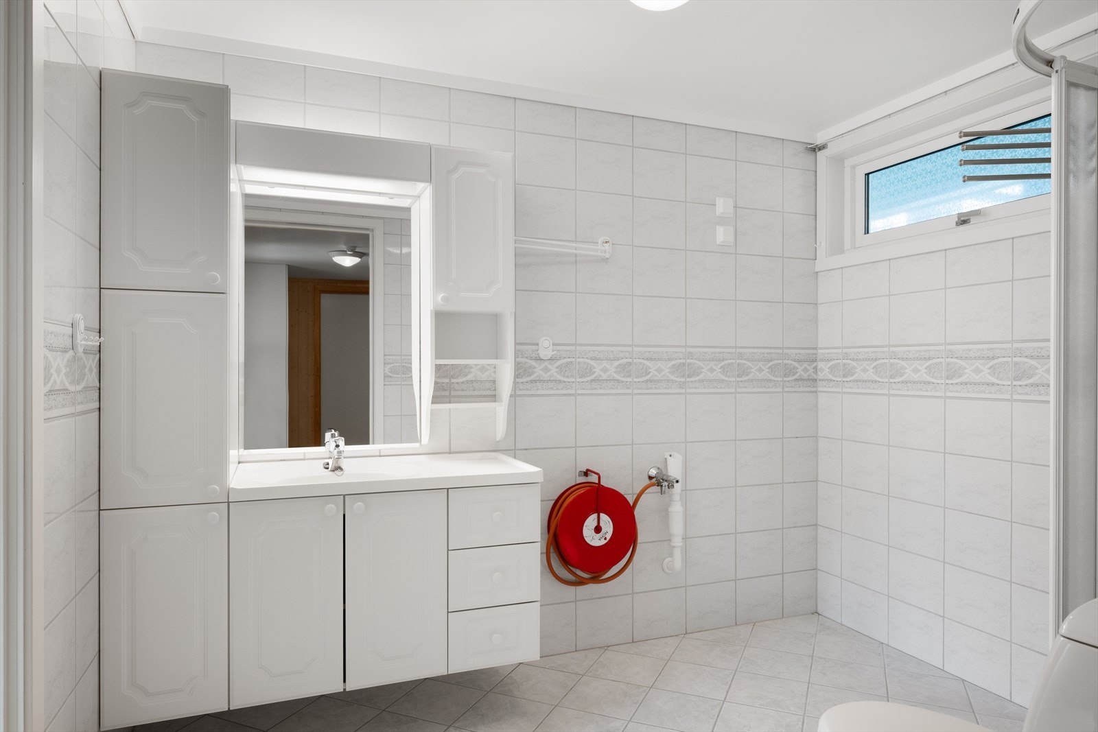 Badet er utstyrt med dusjhjørne, servantinnredning og har opplegg for vaskemaskin. Galleribilde