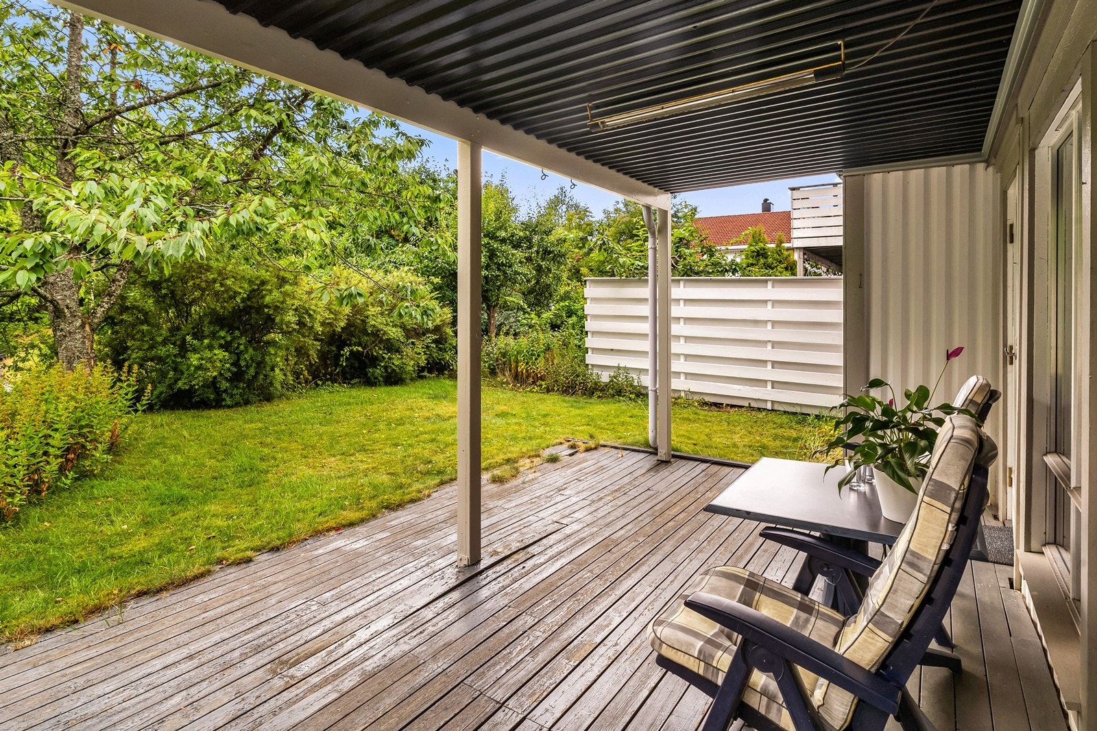 Terrassen har videre tilgang til gressplen, omkranset av hekk og beplantning, noe som skaper en skjermet uteplass. Galleribilde