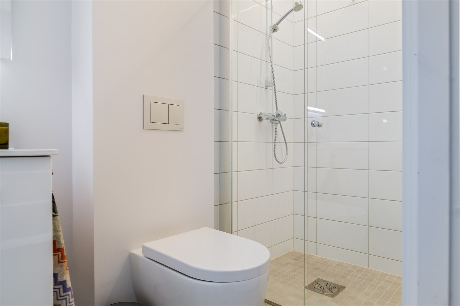 Badet i 3. etasjen er innredet med veggmontert toalett, dusjvegg og servant i møbel Galleribilde