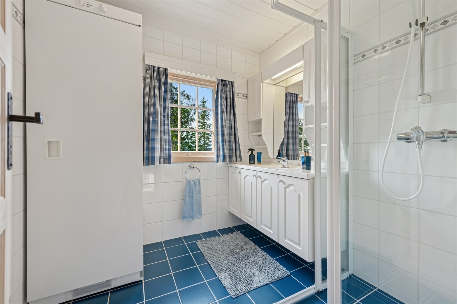 Bad med flislagt gulv og varmekabler. Badet er utstyrt med dusjhjørne, lys baderomsinnredning og tørkeskap. Galleribilde