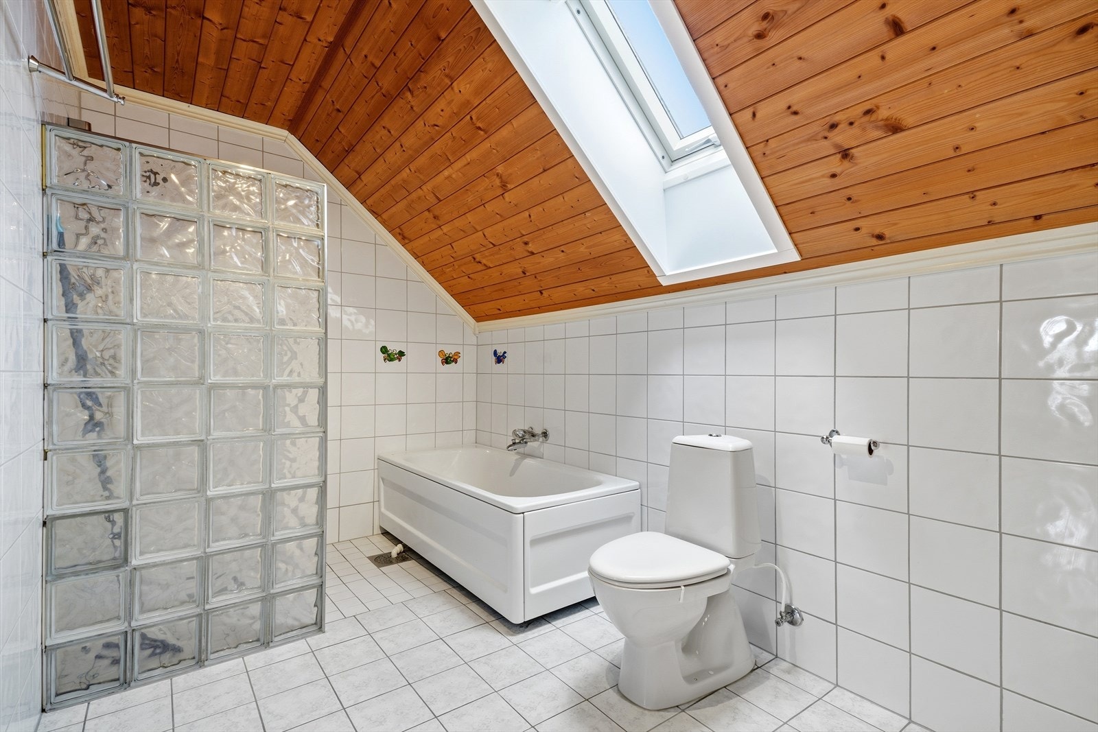 Badet er innredet med både badekar og en dusjnisje av glassbyggerstein. Galleribilde