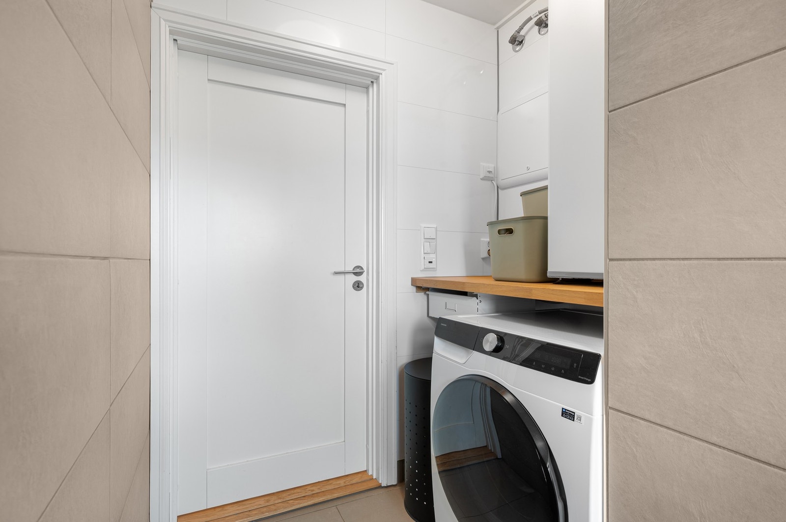 Idet man kommer inn på badet har man en praktisk løsning for plassering av vaskemaskin. Her befinner også varmtvannstanken seg - over den praktiske bekeplaten. Galleribilde
