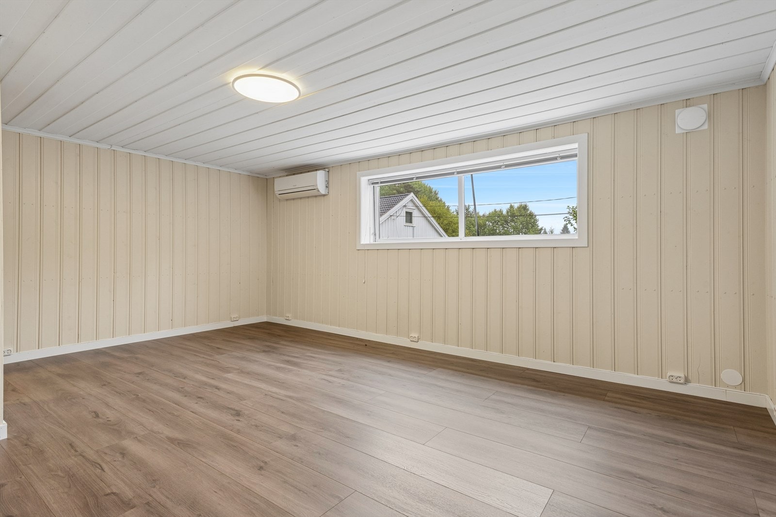 Innredet rom i underetasjen med varmepumpe og malt trepanel. Galleribilde