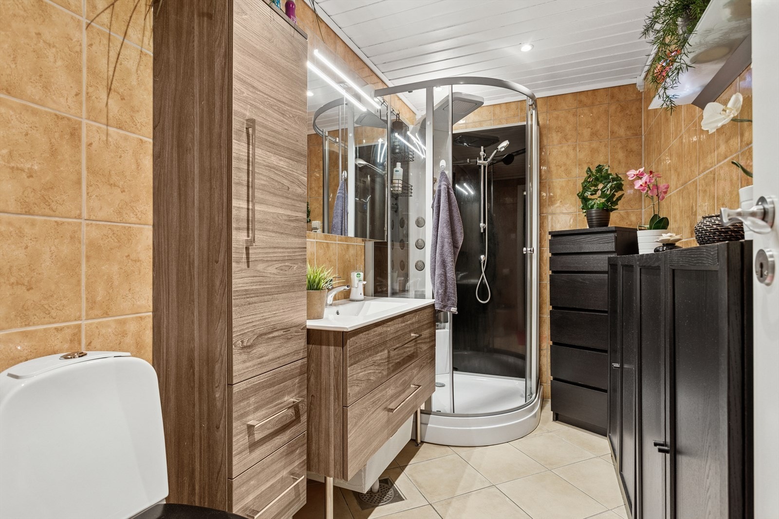 Badet er utstyrt med gulvmontert toalett, ny baderomsinnredning fra 2020, og nytt dusjkabinett fra 2020. Flislagte vegger og malt panel i himling. Galleribilde