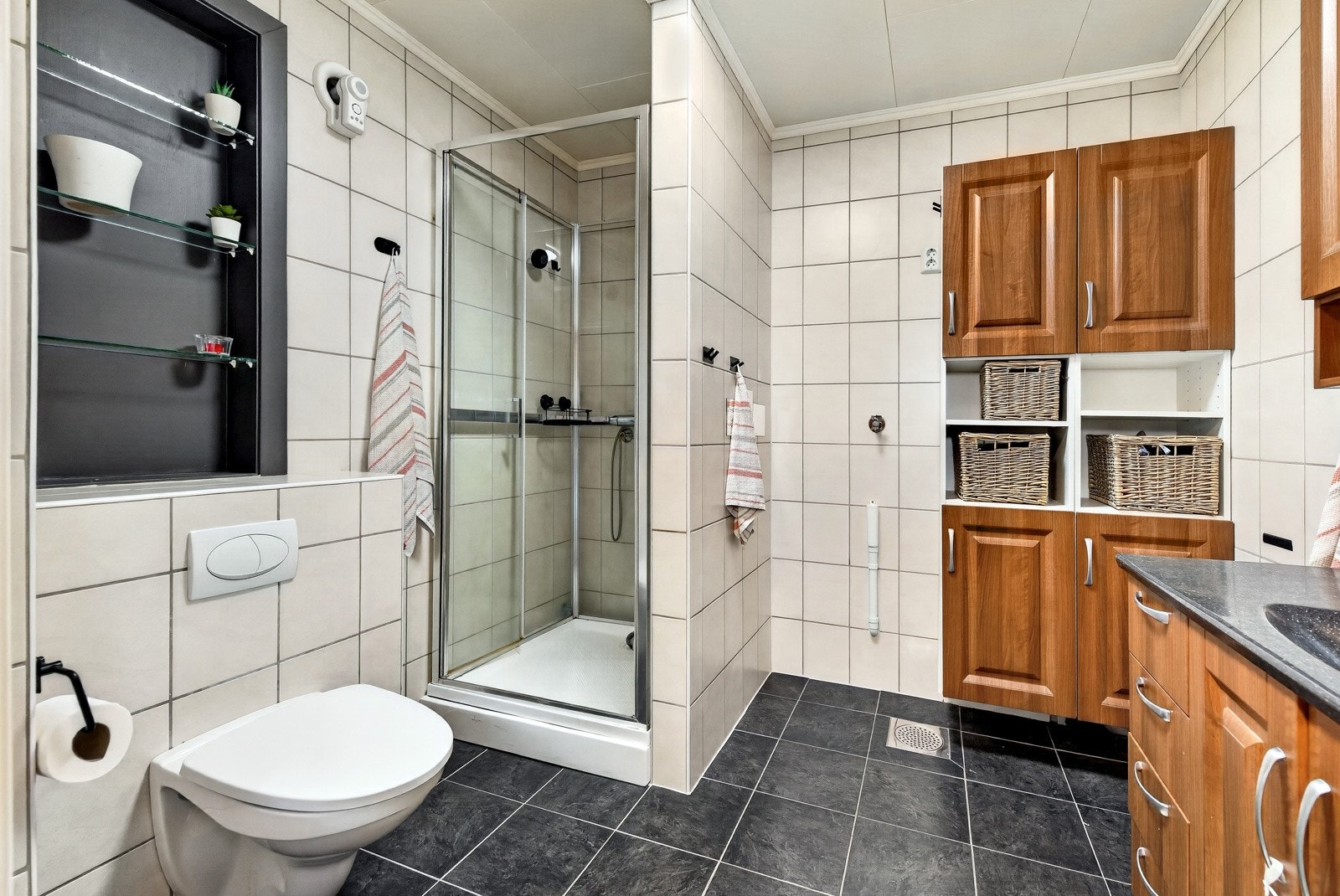 Badet har dusjløsning med dusjkabinett, fliser på vegger og gulv, gulv med behagelig gulvvarme, og opplegg for vaskemaskin. Galleribilde