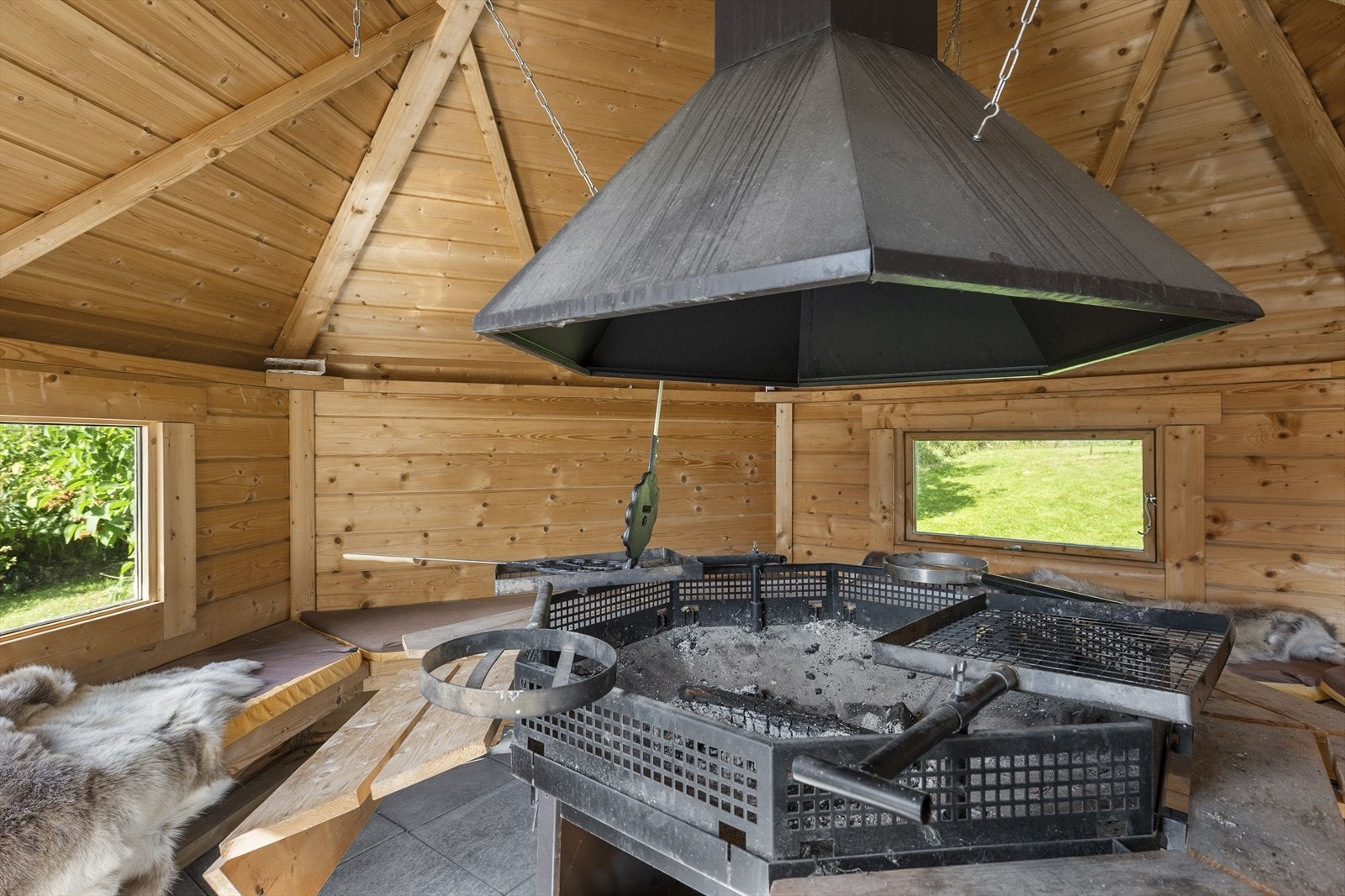 Grilhytte innvendig med sittebenker og grill i midten. Galleribilde