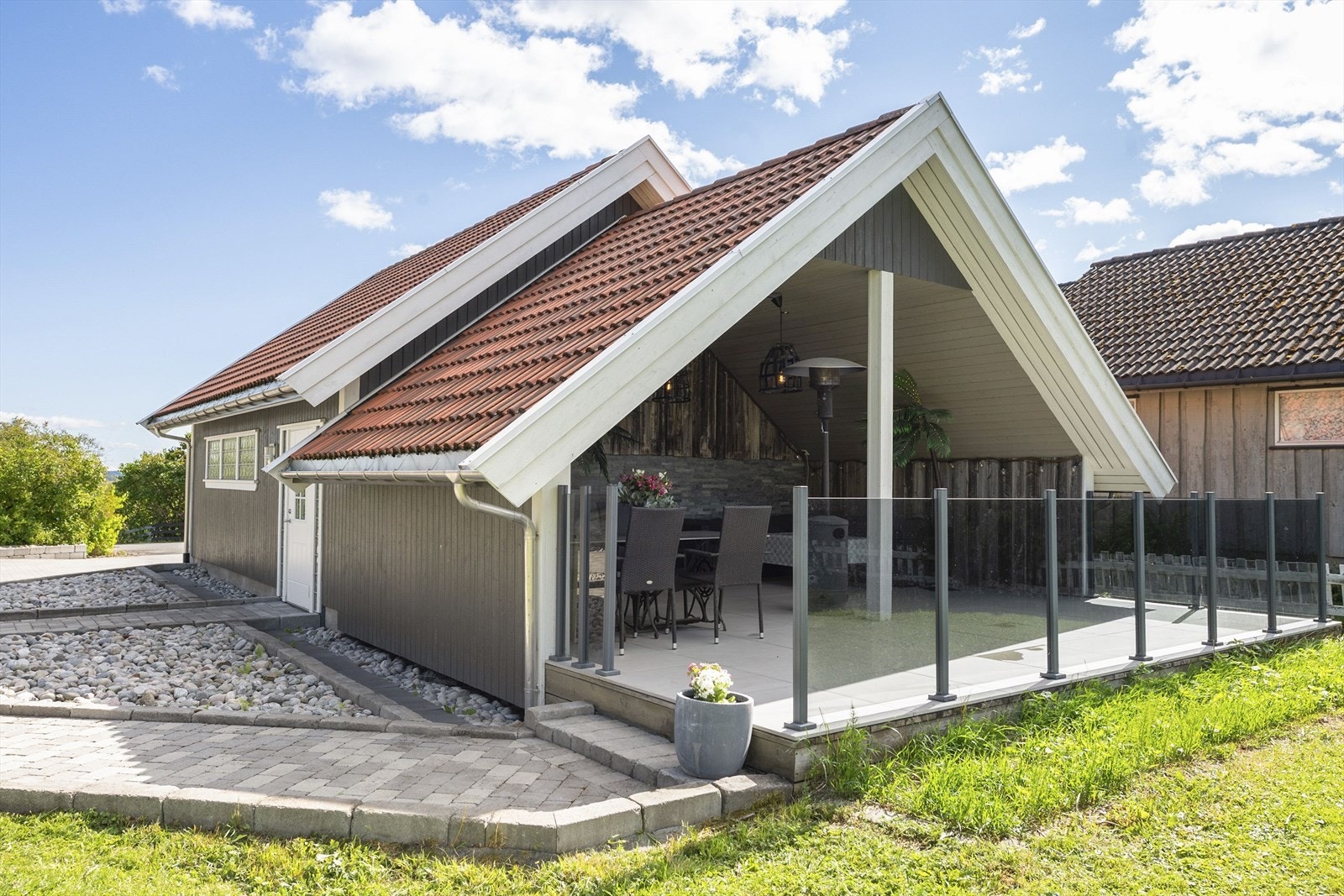 Tilbygget overbygget terrasse mot vest med glassrekkverk, fliser innlagt strøm etc. Galleribilde