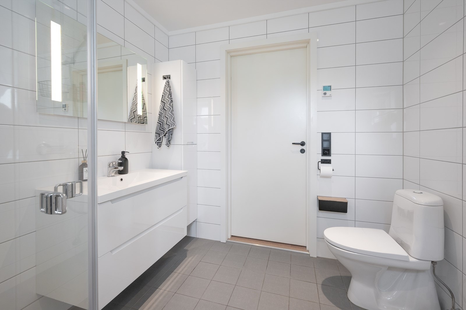 Badet er utstyrt med vegghengt toalett og heldekkende servant med skuffer Galleribilde