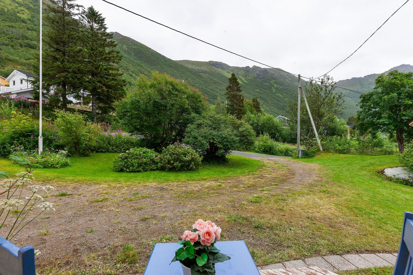 Romslig tomt med grøntarealer, beplantning og gruset adkomst. Galleribilde