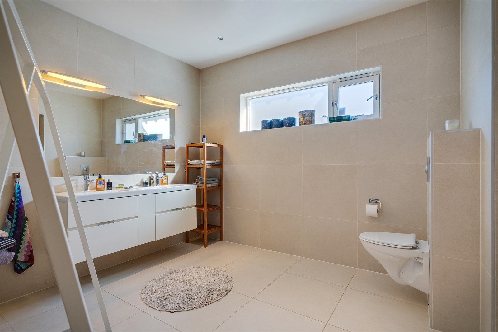 Romslig, flislagt bad med dobbel servant og vegghengt toalett. Flisene på badet er Villeroy & Boch. Galleribilde