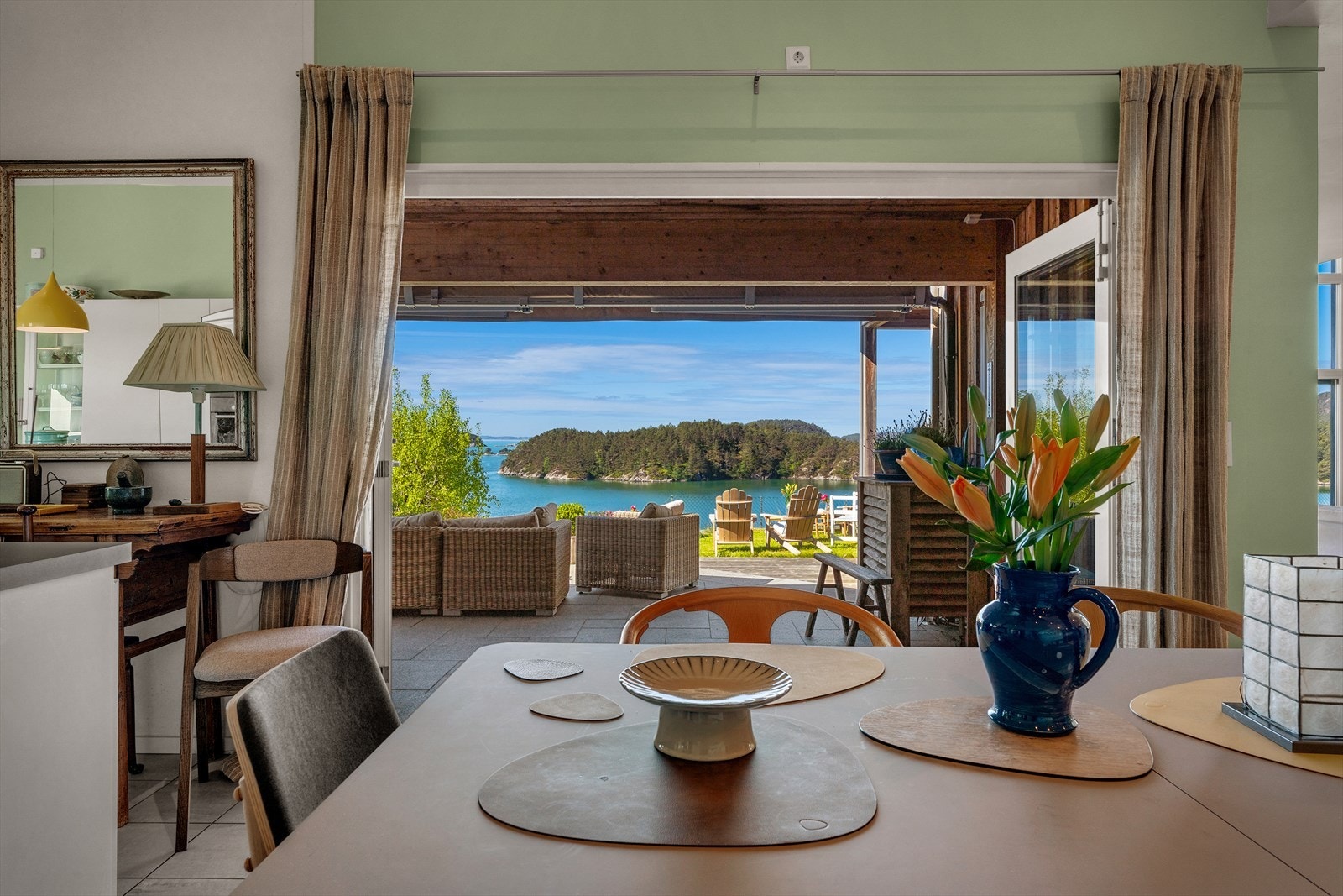 Fra spisebordet ser man rett ut på den overbygde terrassen og sjøen. Galleribilde