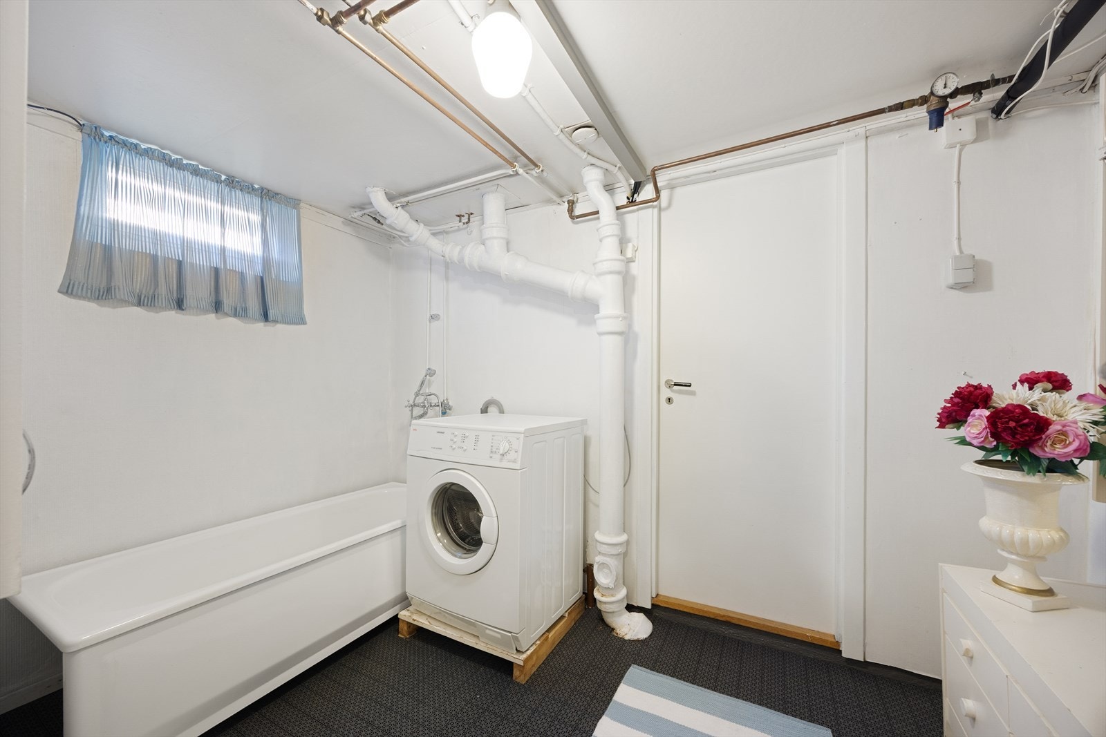 Praktisk vaskerom i kjelleren med opplegg for vaskemaskin og et badekar. Galleribilde