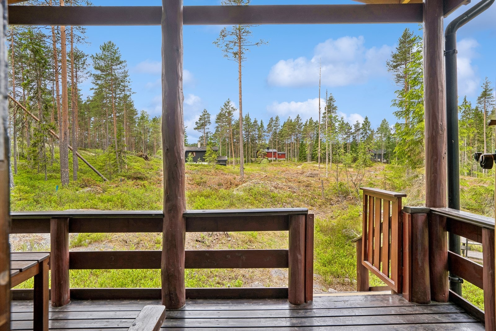 Overbygget terrasse utenfor inngangen. Det er flere hytter i nærheten. Galleribilde