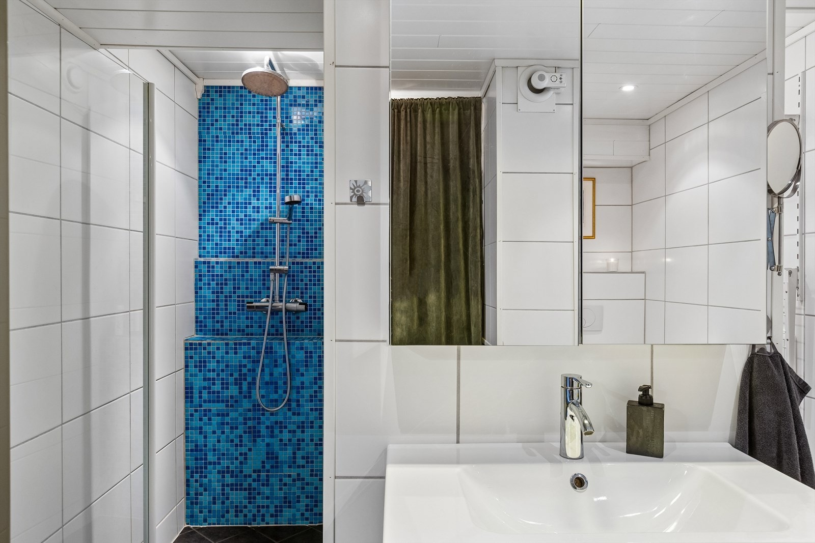 Badet er flislagt og utstyrt med dusj, servant med underskap, wc samt vaskemaskin. Galleribilde