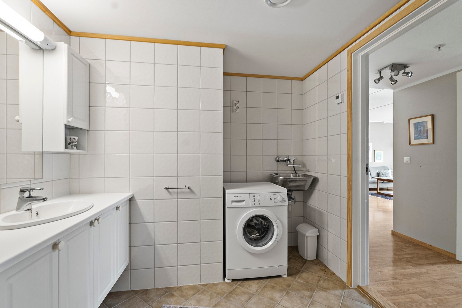 Badet er kombinert vaskerom med opplegg for vaskemaskin og praktisk skyllekar. Galleribilde