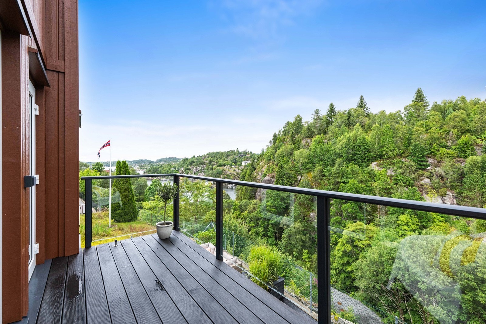 Terassen er belagt med terrassebord og rekkverk i glass og metall. Galleribilde