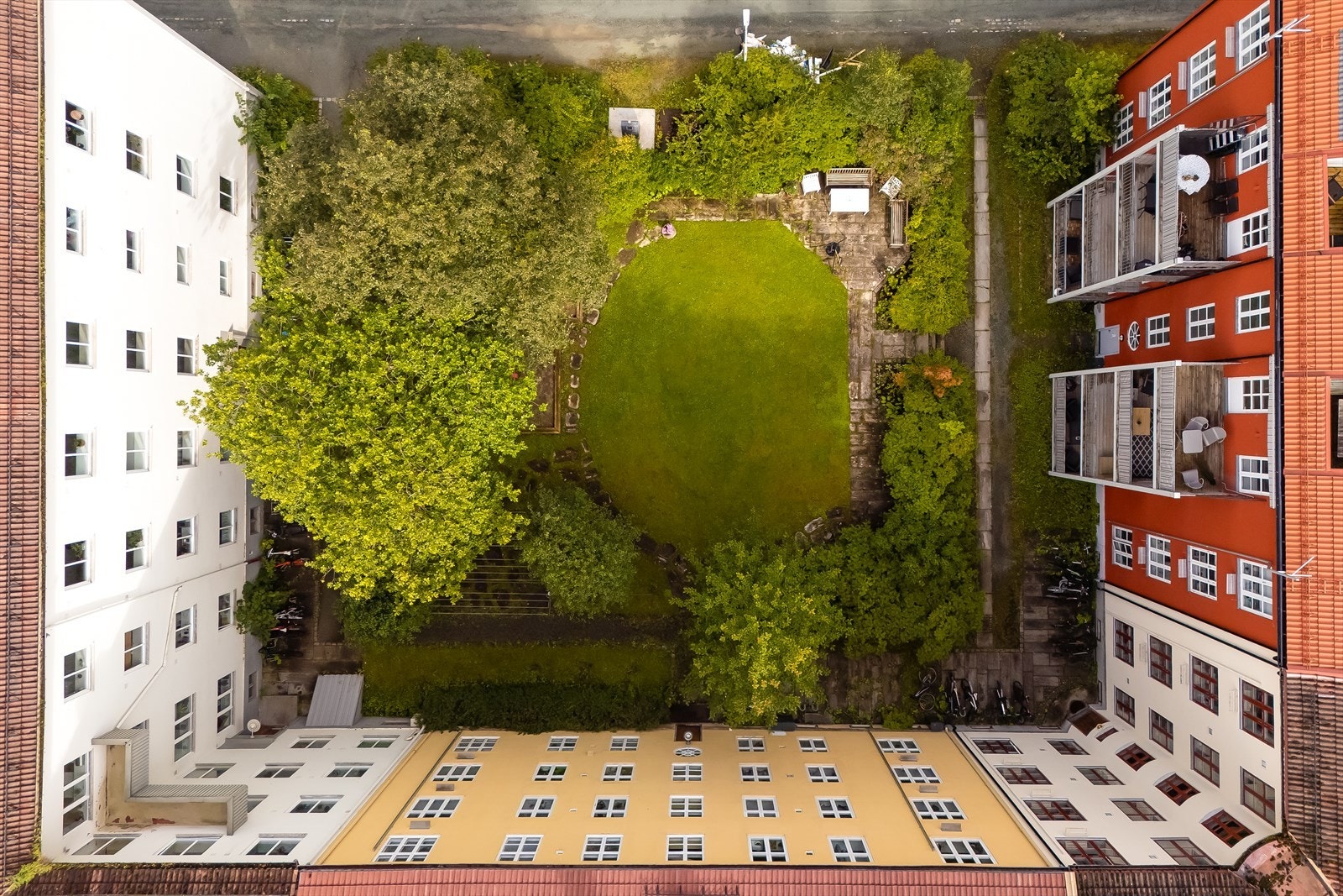 Bakgården ligger skjermet til og har gode solforhold. Det er etablert sykkelparkering, sittegrupper og lekeplass. Galleribilde