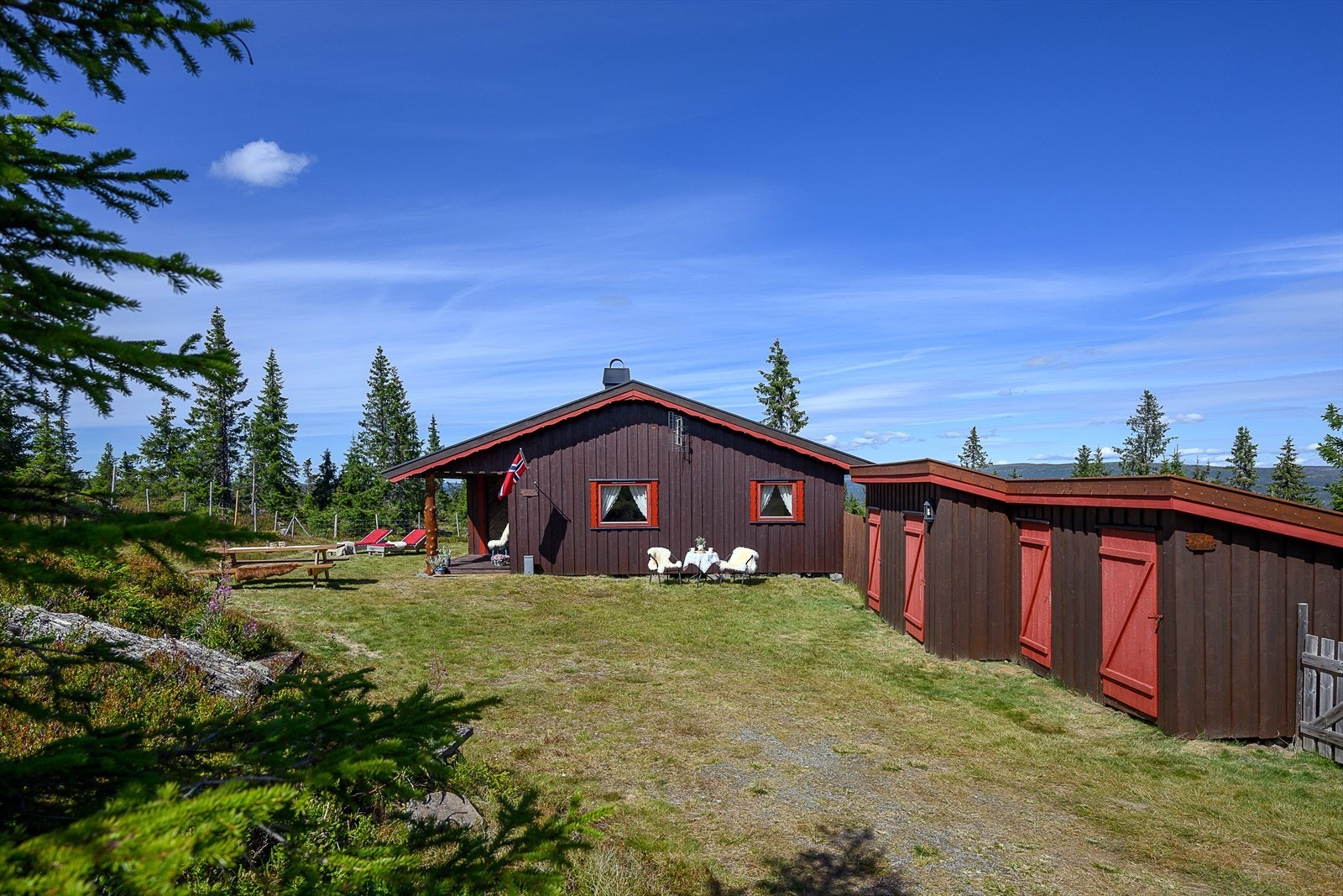 Hytta og uthuset har en enhetlig stil med beiset tømmermannspanel. Galleribilde