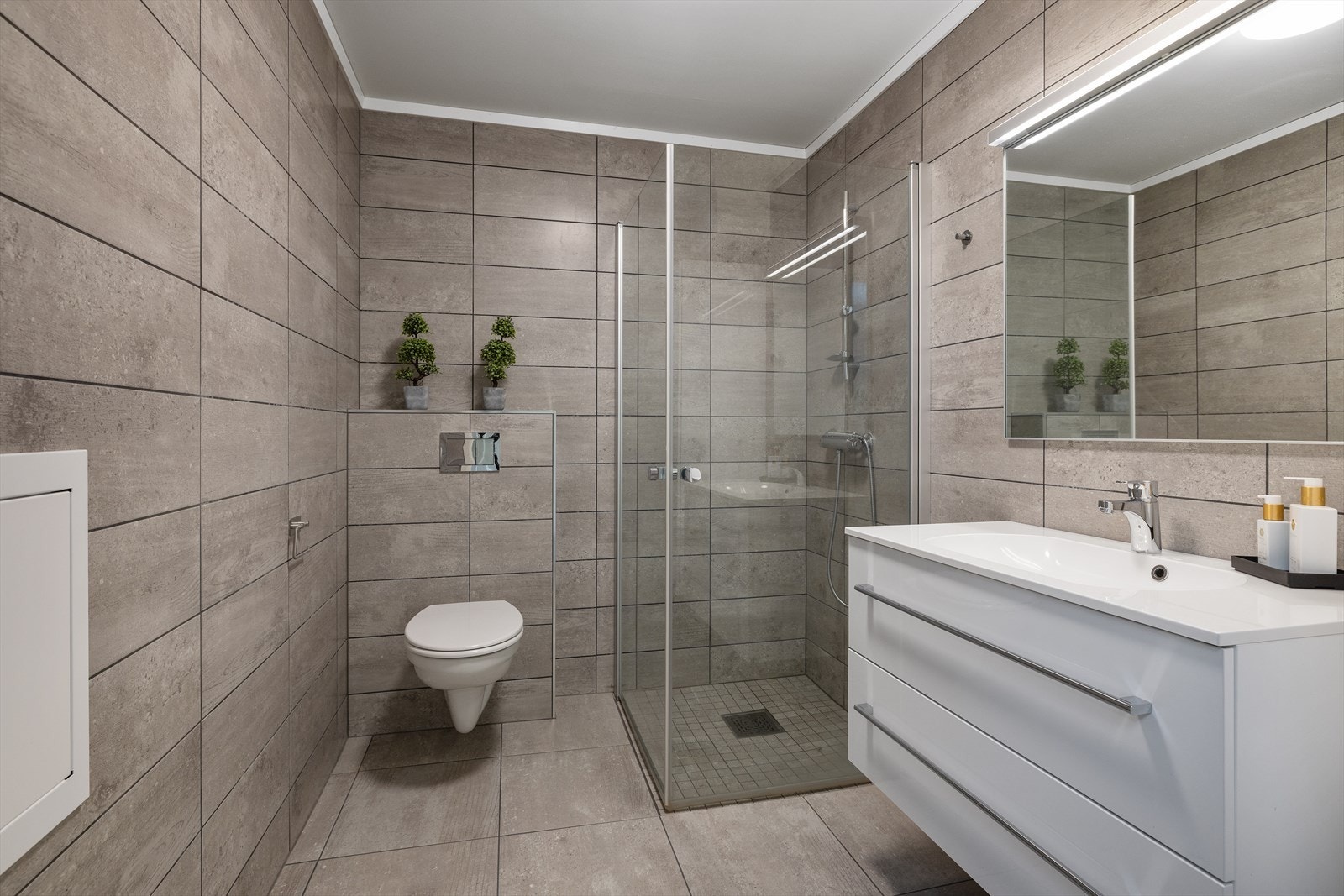 Badet har elektrisk gulvvarme, vegghengt toalett og dusjhjørne med glassdører. Galleribilde