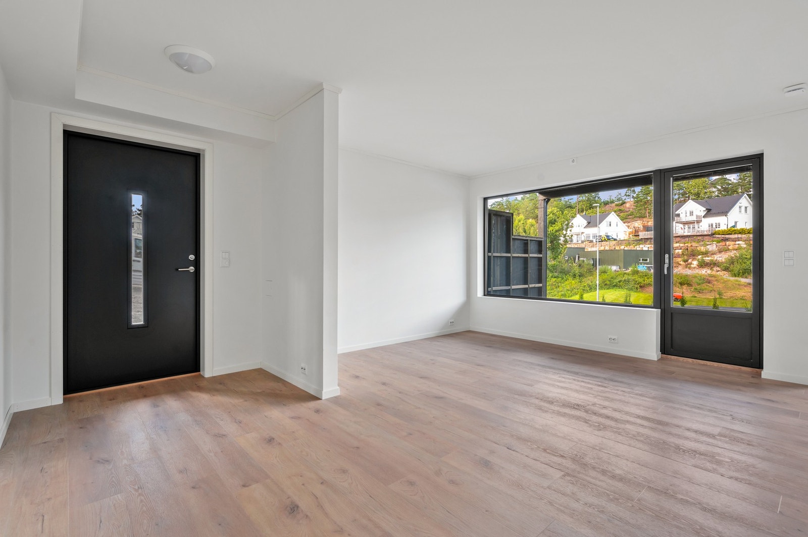 Innbydende entré med moderne inngangsdør og en luftig overgang til boligens oppholdsrom. Galleribilde