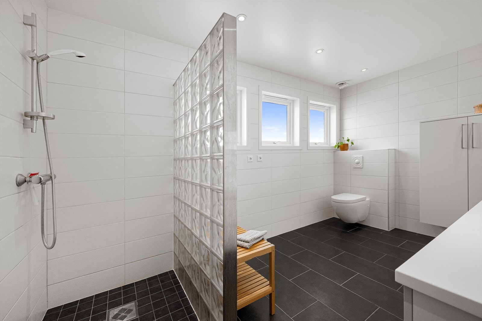 Badet har flislagte overflater, dusjnisje og vegghengt toalett. Galleribilde