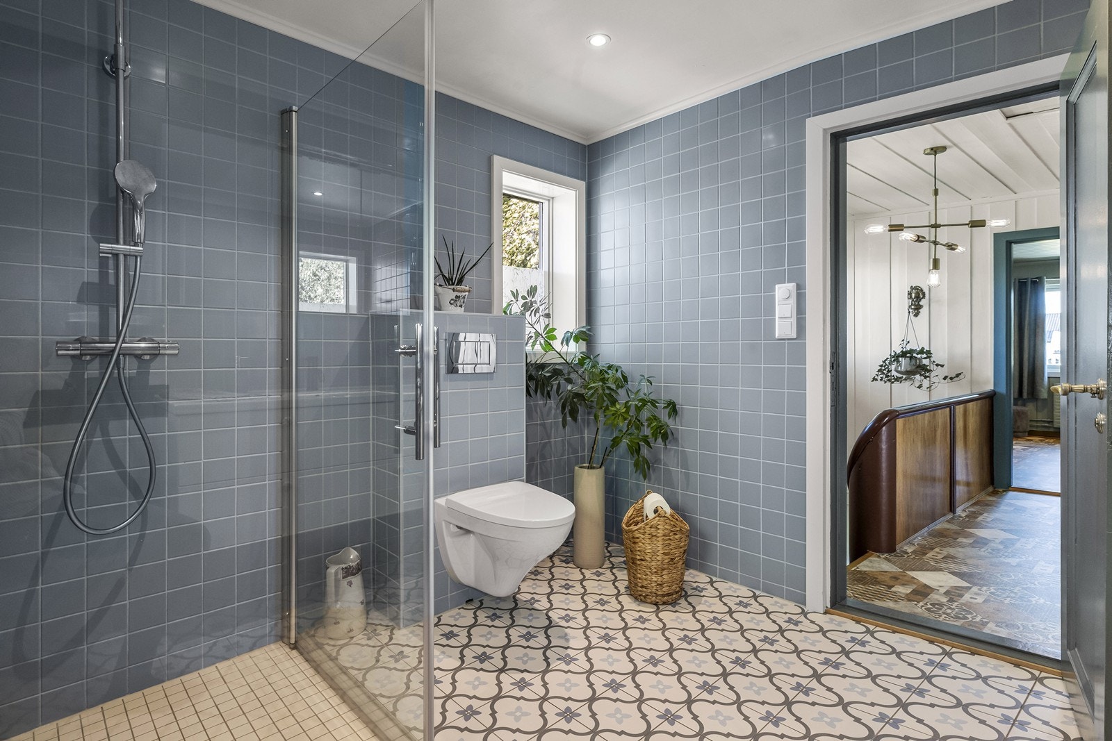 Badet har vannbåren gulvvarme, servantinnredning og speilskap, vegghengt toalett og dusjhjørne med innfellbare glassdører. Galleribilde