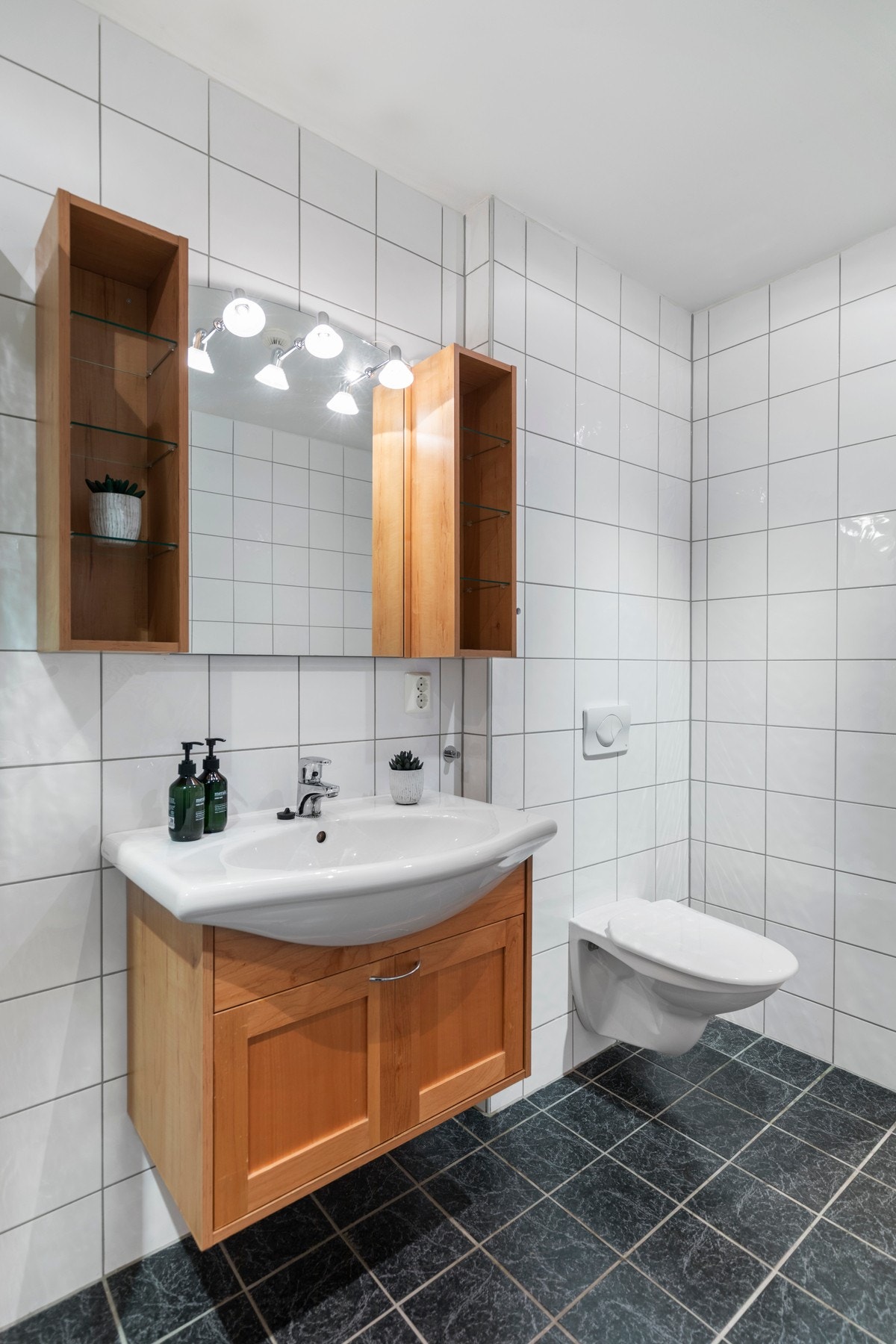 Badet er utstyrt med blant annet varmekabler i gulv, dusj med dusjvegger, vegghengt toalett og opplegg for vaskemaskin/tørketrommel. Galleribilde