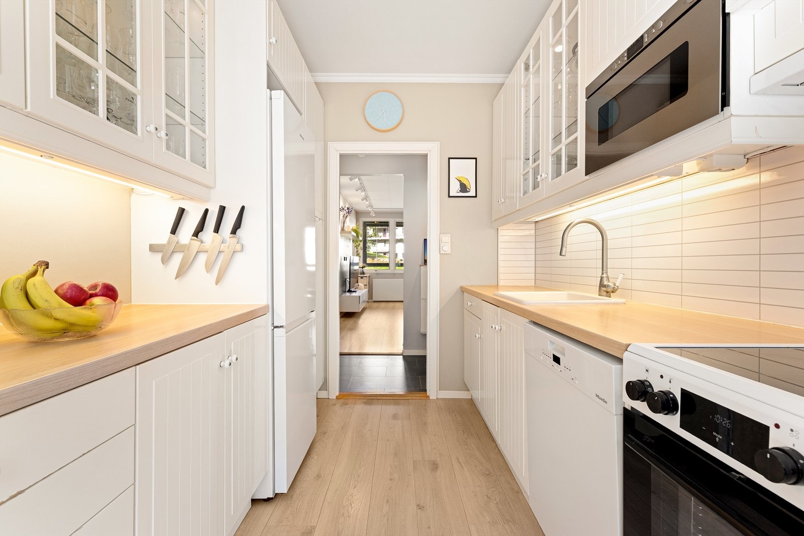 Kjøkkenet inneholder innredning fra IKEA (2004) med profilerte, hvite fronter og laminert benkeplate. Over benken er det montert Kitchenboard for enkel rengjøring. For øvrig er det opplegg for komfyr og oppvaskmaskin, ventilator & integrert mikro (201 Galleribilde