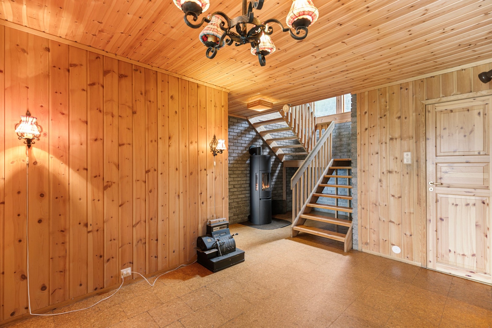 Videre inn har du hallen med korkgulv og panelvegger. Her har du tilkomst til hovedetasjen og oppvarming fra varmepumpe og nyere vedovn. Galleribilde