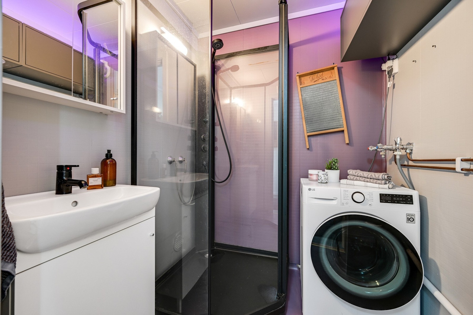 Badet er innredet med dusjkabinett, servantinnredning og opplegg for vaskemaskin. Galleribilde