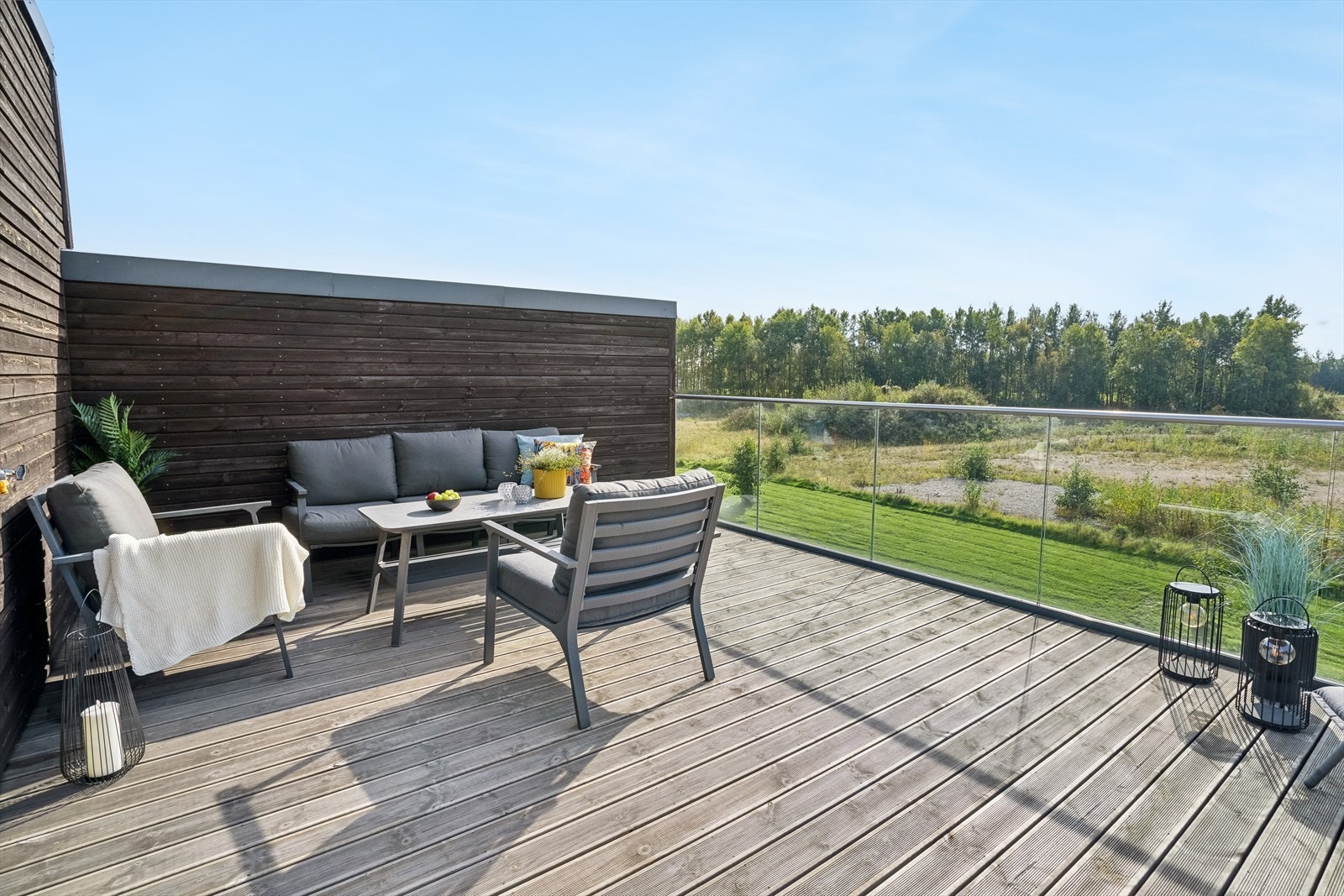 Glassrekkverket åpner opp utsynet mot de grønne omgivelsene og understreker terrassens luftige og usjenerte preg. Galleribilde