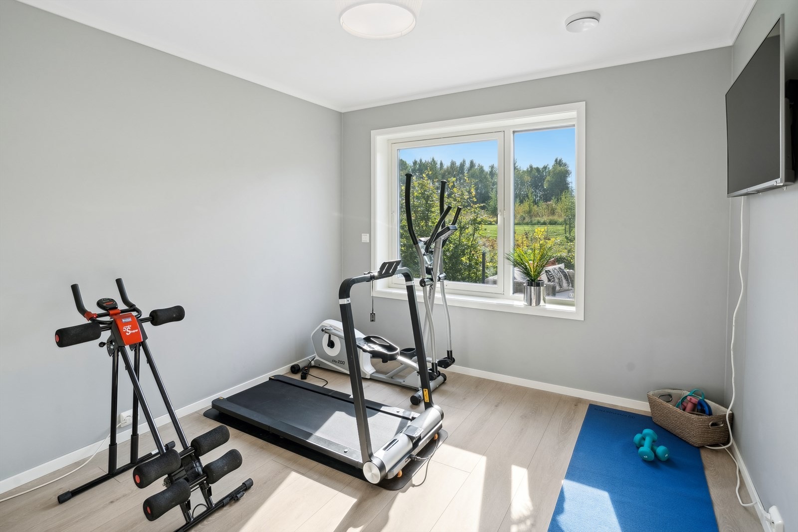 Et fleksibelt soverom som i dag er innredet som treningsrom, med godt lysinnslipp og utsyn mot grønne omgivelser. Galleribilde