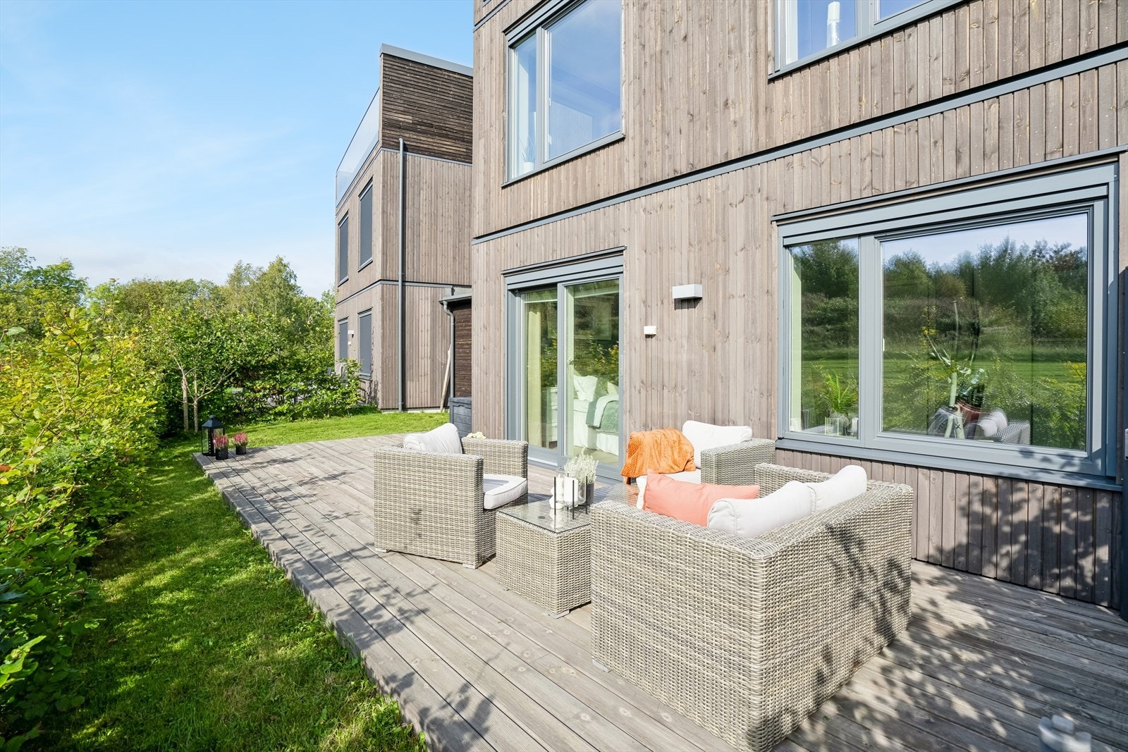 Terrassen strekker seg langs boligen og gir flere møbleringsmuligheter, samtidig som hagen rammes inn av velstelt og frodig beplantning. Galleribilde