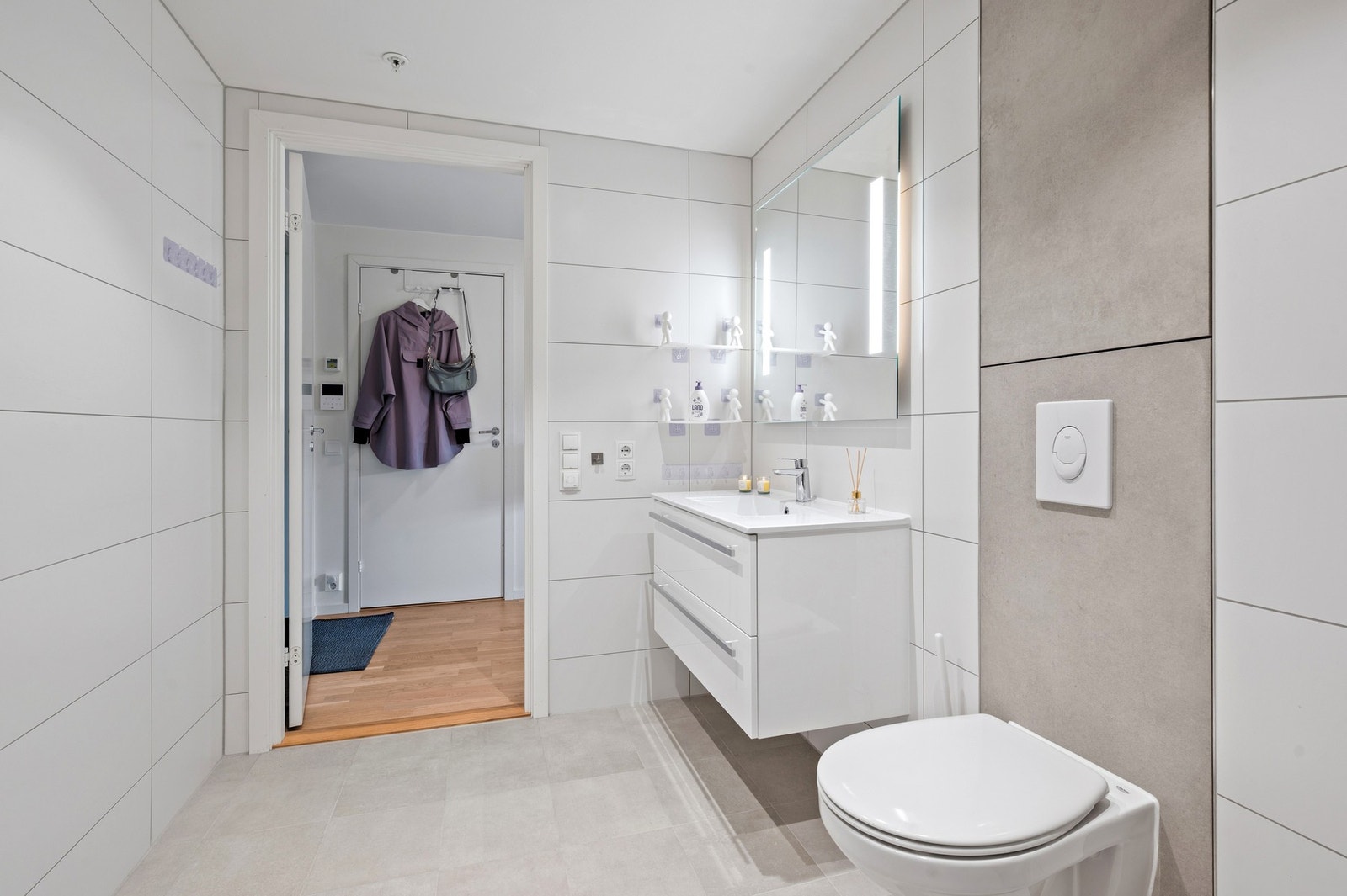 Badet er innredet med vegghengt toalett og og servant med underskap, speil, dusjnisje med innfellbare dører og opplegg for vask- og tørkemaskin Galleribilde