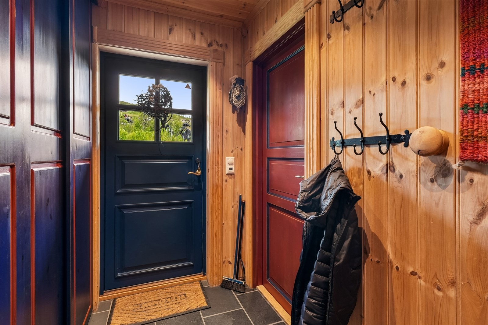 Hovedytterdøren er i malt tre med glassfelt og leder inn til en praktisk entré. Her er det garderobeskap i aldringsmalt heltre med hyller og skyvefronter, som gir en ryddig oppbevaring av yttertøy og sko. Galleribilde