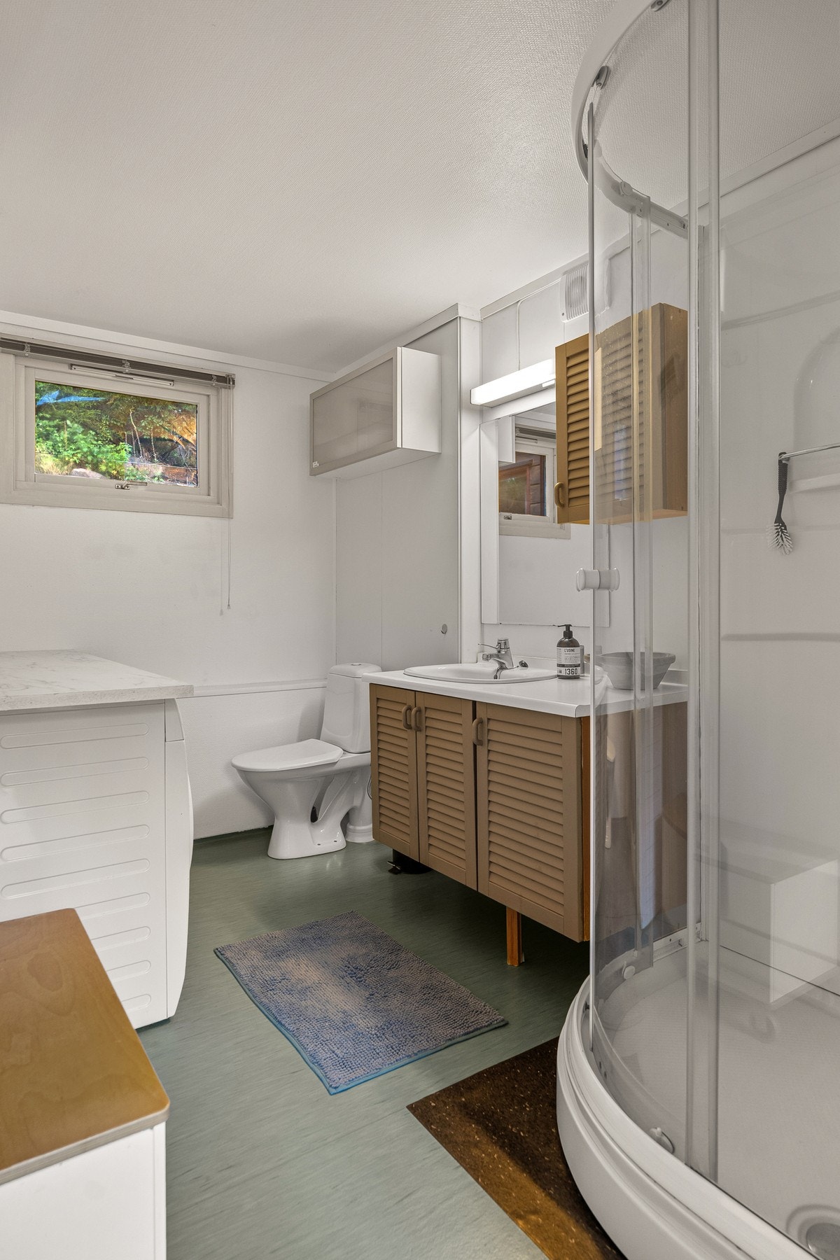 Badet i hybelen er innredet med dusjkabinett, servant med skap, opplegg til vaskemaskin og toalett Galleribilde