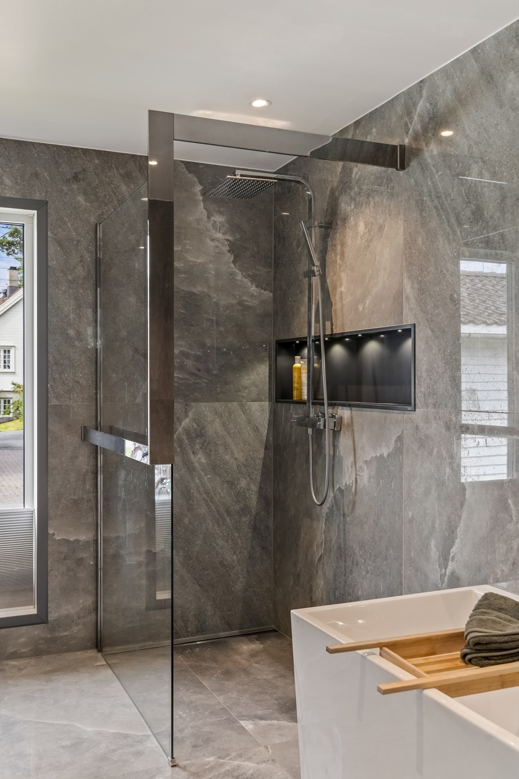 Badet er utstyrt med både dusjnisje og badekar, samt en praktisk nisje for oppbevaring. Galleribilde