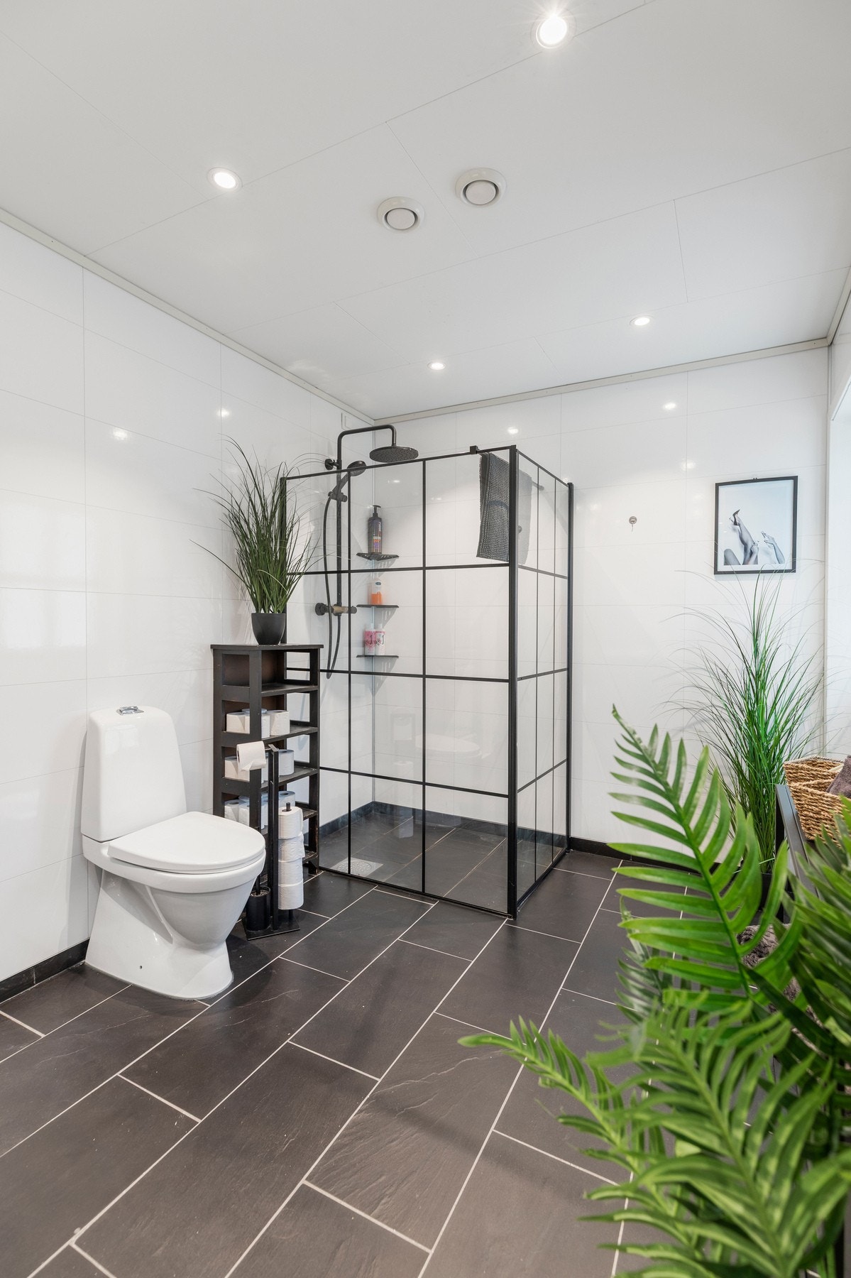 Badet er utstyrt med varmekabler i gulv, spotlights i himling, dusjhjørne med glassvegg/dør, hel servantplate med to vasker og underskap. Galleribilde