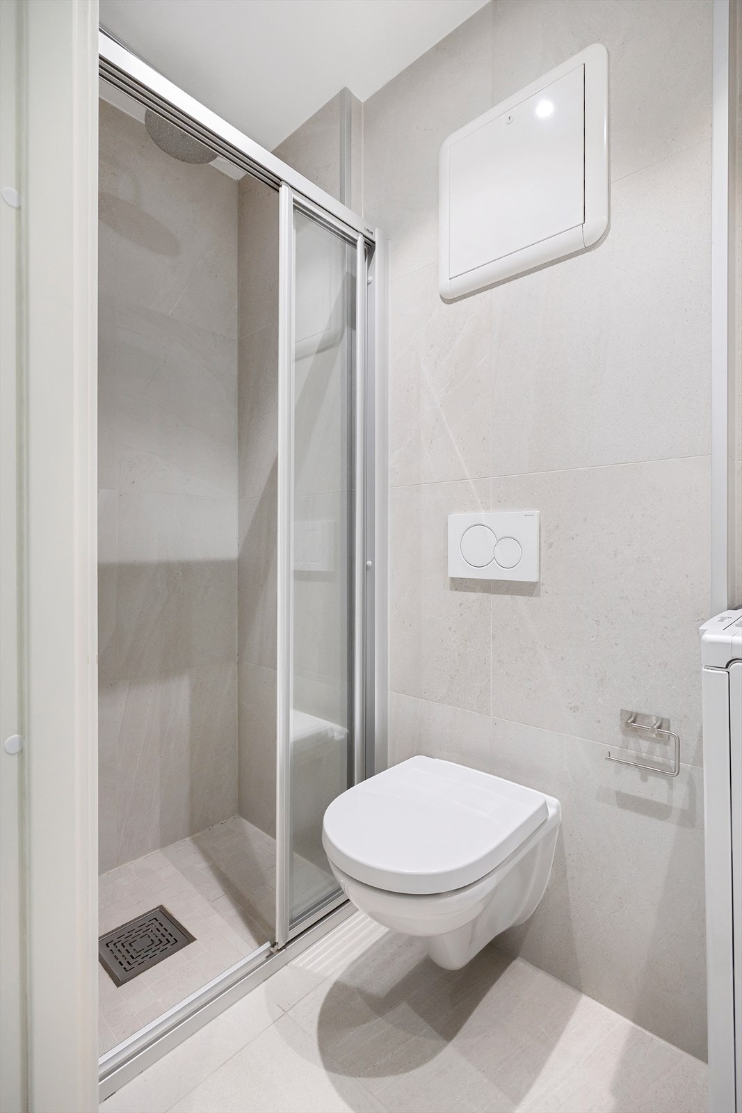 Badet er innredet med baderomsmøbel med glatte fronter, servant, vegghengt toalett, dusjhjørne og opplegg for vaskemaskin. Galleribilde