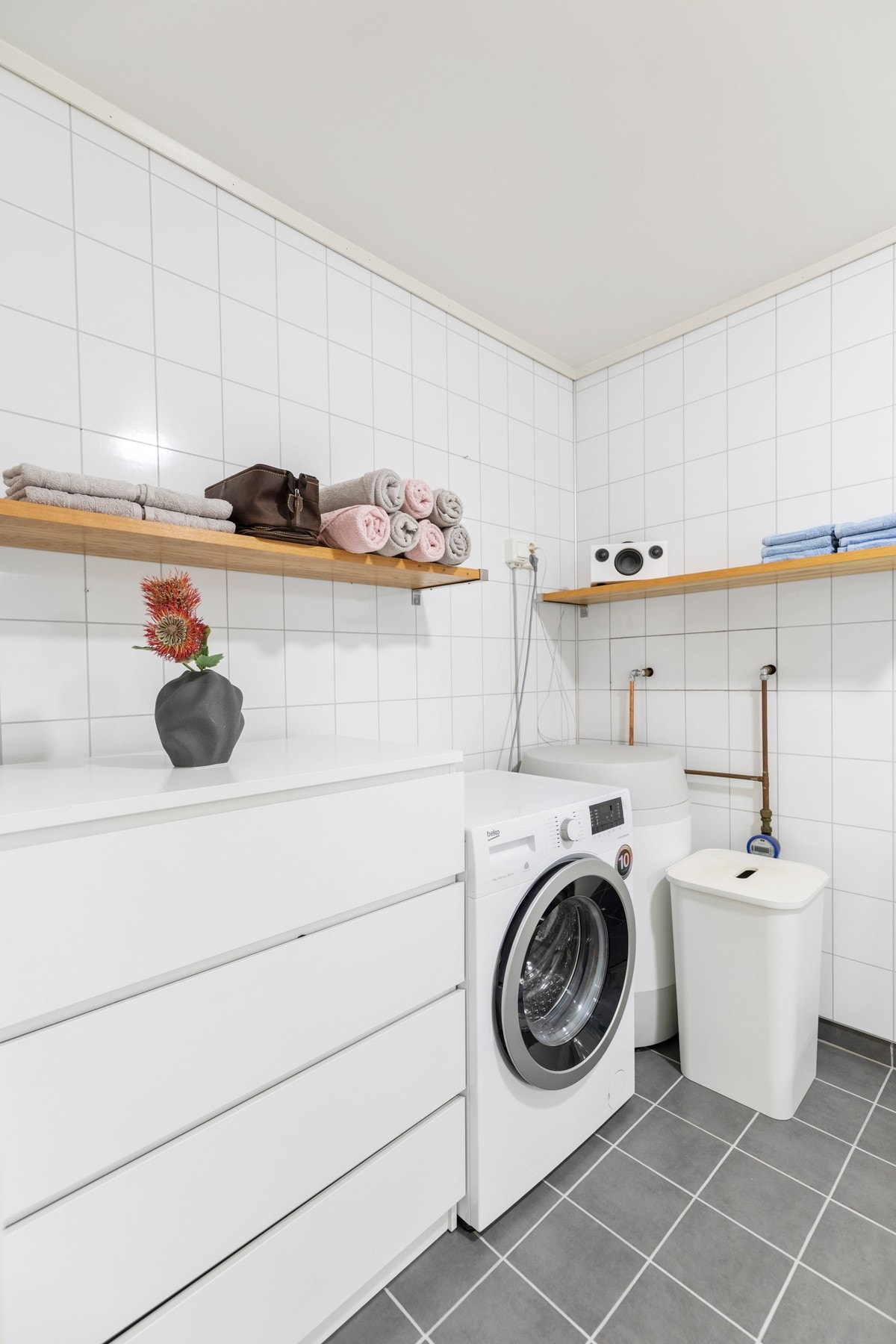 Videre er badet utstyrt med dusjkabinett, toalett, servant med underskap, vv-bereder, opplegg for vaskemaskin, stoppekran, vannmåler og ventilasjon i himling. Galleribilde