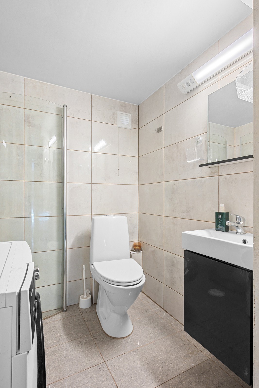 Badet i underetasjen er fra 2021 og er innredet med dusjhjørne med innfellbare glassdører, servant, speil, toalett og opplegg for vaskemaskin. Galleribilde