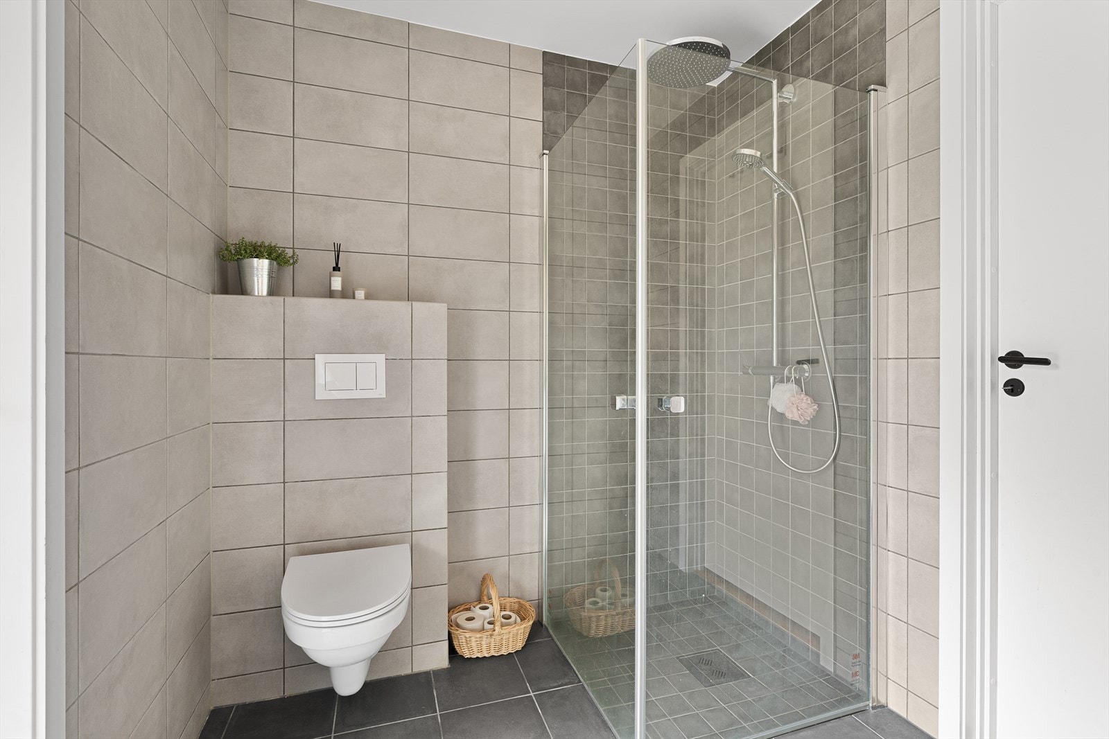 Badet inneholder en dusjnisje med innfellbare dusjdører, regndusj, vegghengt toalett, samt baderomsinnredning med speil over. Galleribilde