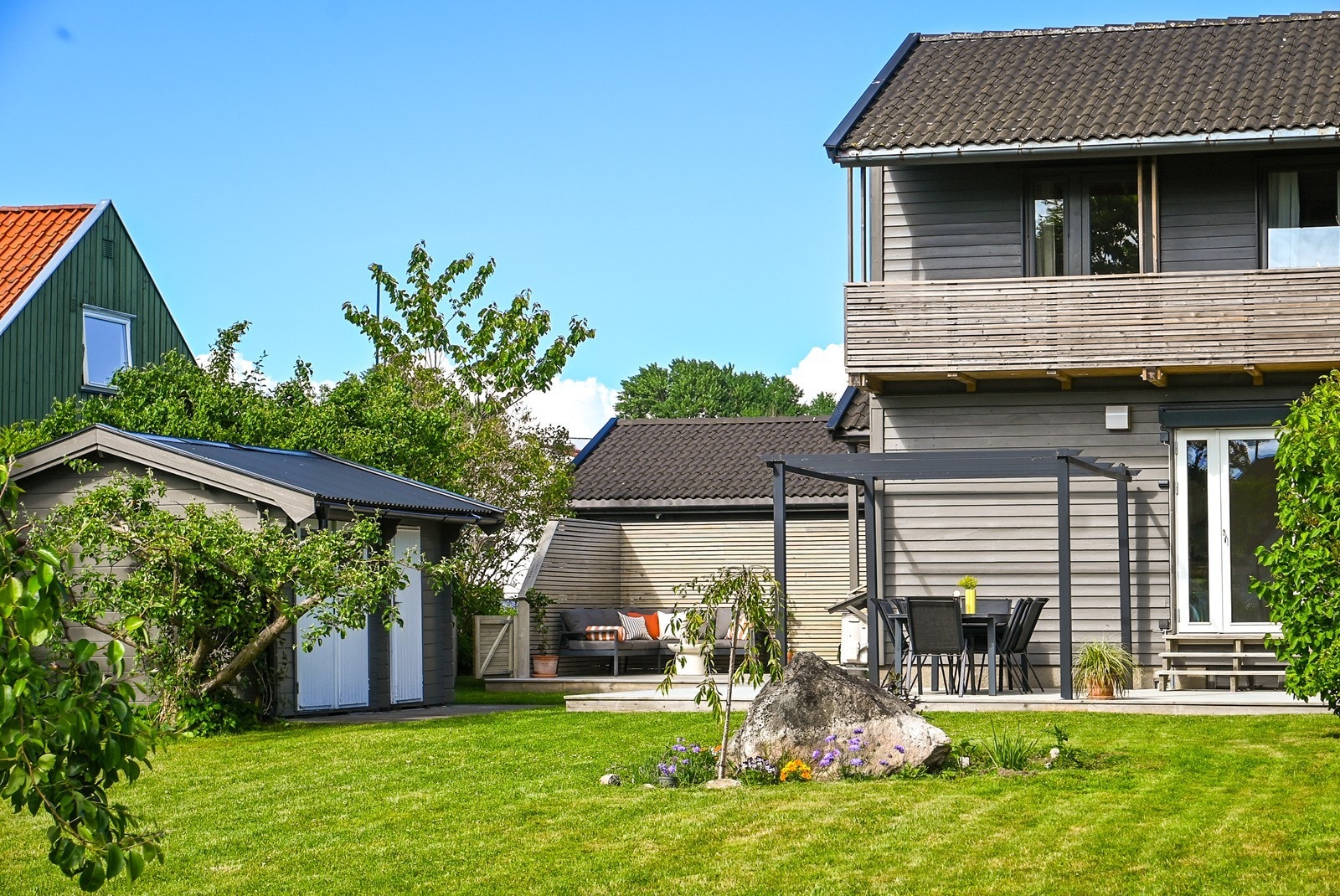 Velstelte plenarealer og beplantning skaper en hyggelig ramme på baksiden av boligen. Galleribilde