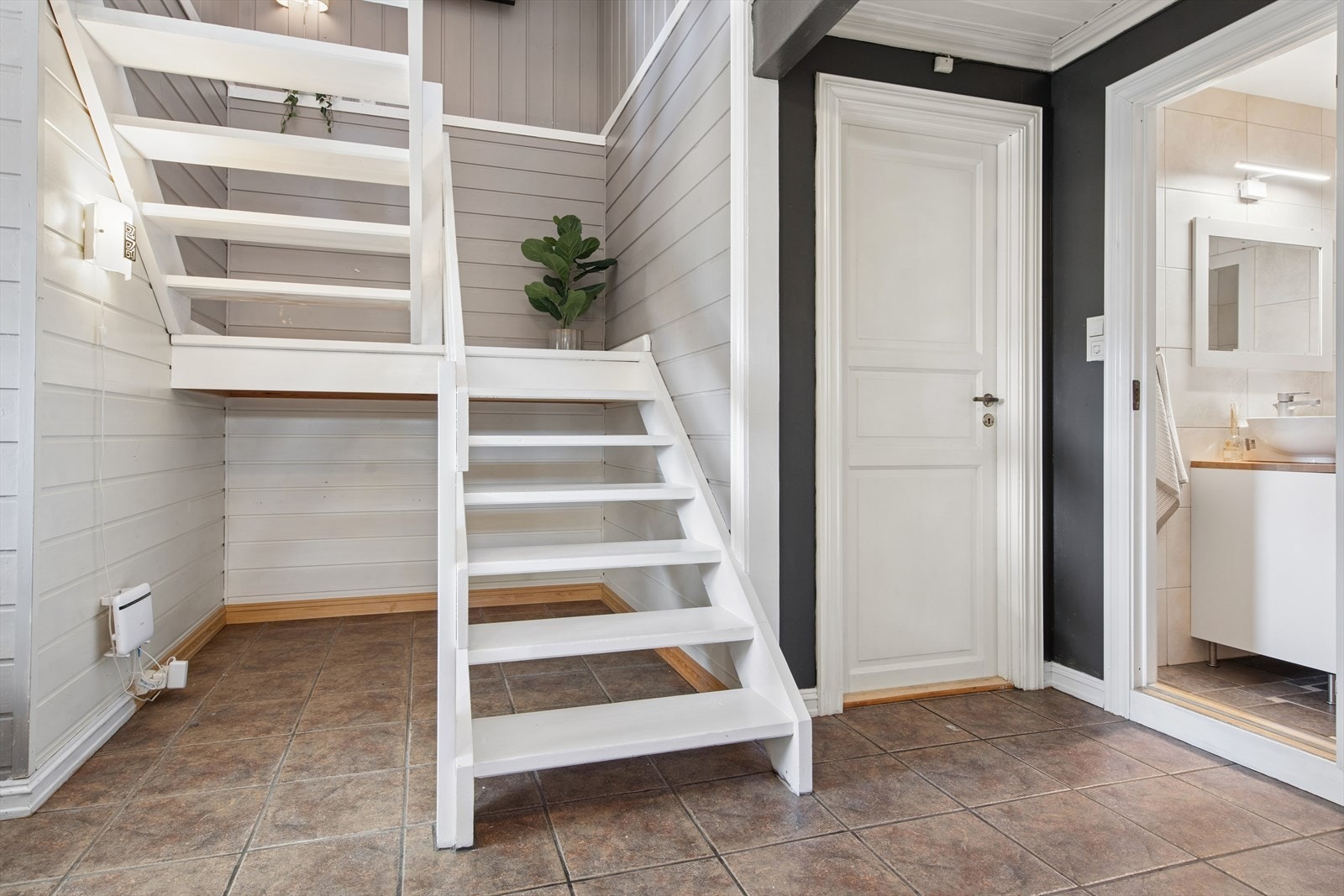 Fra hallen fører en malt tretrapp opp til hovedetasjen. Døren til høyre leder inn til badet. Galleribilde