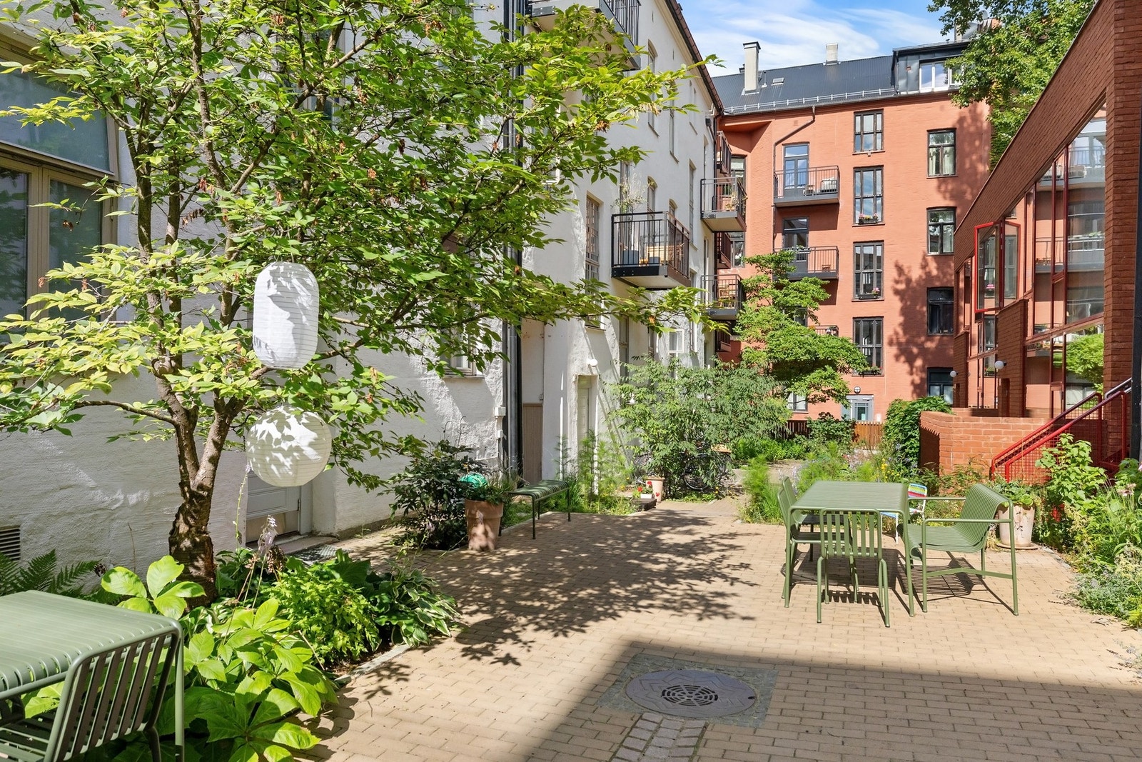 Her er det lagt betongheller, og gårdsrommet er rammet inn av trær og beplantning som skaper en lun og grønn atmosfære Galleribilde
