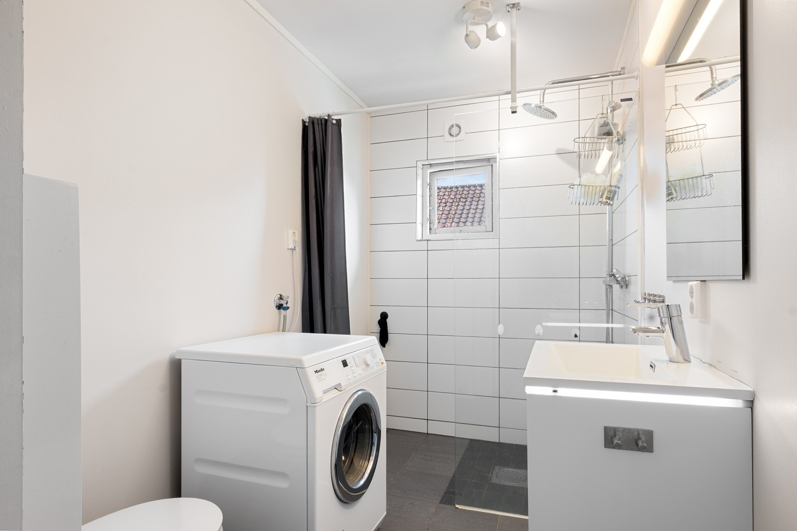 Badet er oppgradert med dels flislagte overflater og gulvvarme. Innredet med servantseksjon med skuffer, dusjhjørne, vegghengt toalett og speil. For klesvask er det opplegg for vaskemaskin. Galleribilde