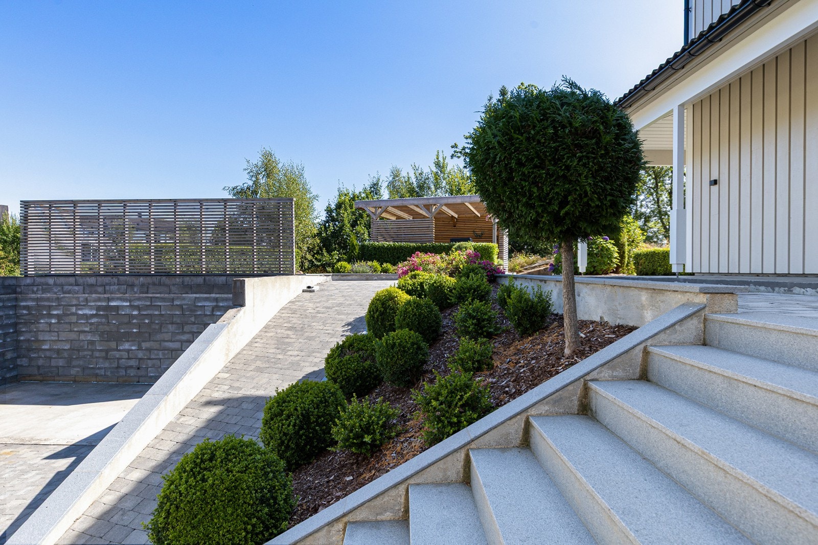 Stilrent inngangsparti med solid steintrapp og lettstelte uteområder. Galleribilde