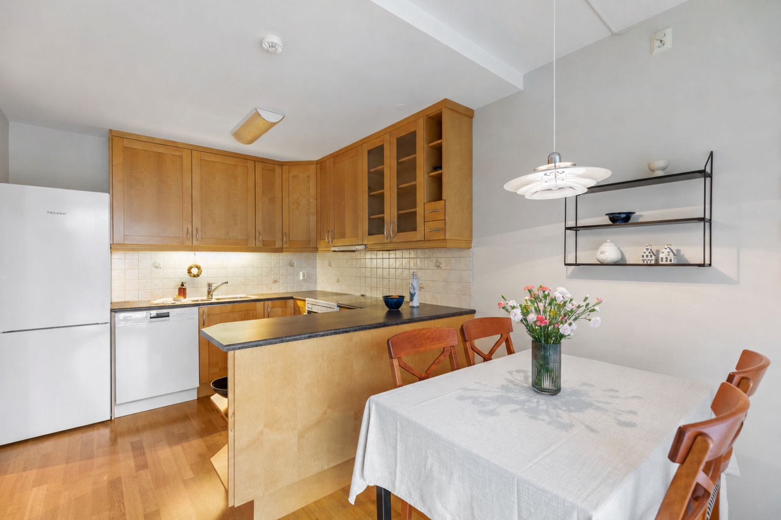 Rommet er utstyrt med ventilator over komfyr, opplegg for oppvaskmaskin, laminat benkeplate med nedfelt oppvaskkum og fliser mellom benk. Galleribilde