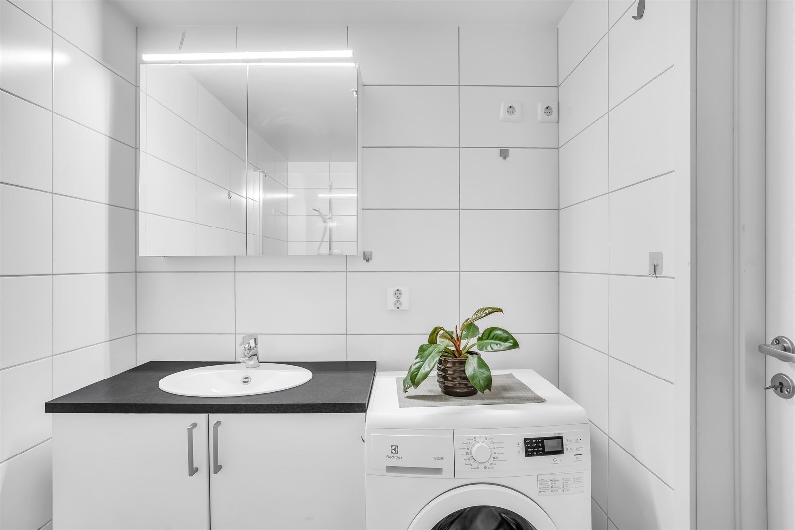 Innredningen består av servant med underskap, speilskap med belysning, vegghengt toalett, dusjsone og opplegg for vaskemaskin. Galleribilde